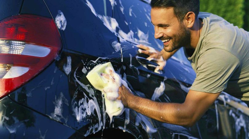 young happy man washing cars sponge how to wash a car ss Feature 810x454